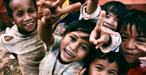 Happy children smiling and reaching towards the camera.