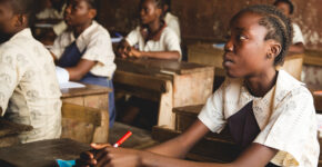 Children attentively learning in a classroom with wooden desks.